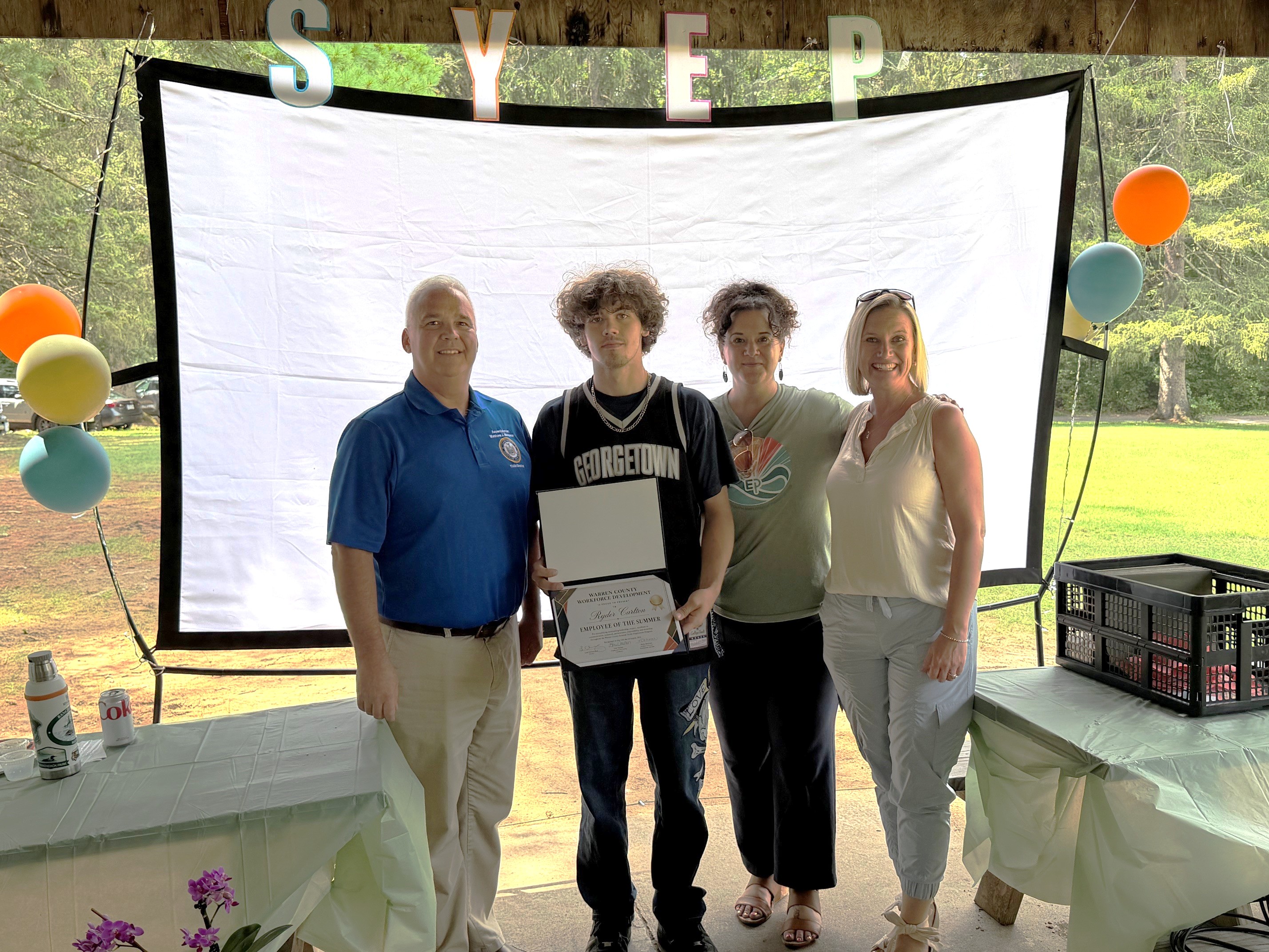 Photo caption -- from left, Assemblyman Matt Simpson, Ryder Carlton, Liza Ochsendorf and Traci Ross, Executive Director of Adirondack Folk School at 2026 Summer Youth Employment Program picnic on Thursday, August 13, 2026.)